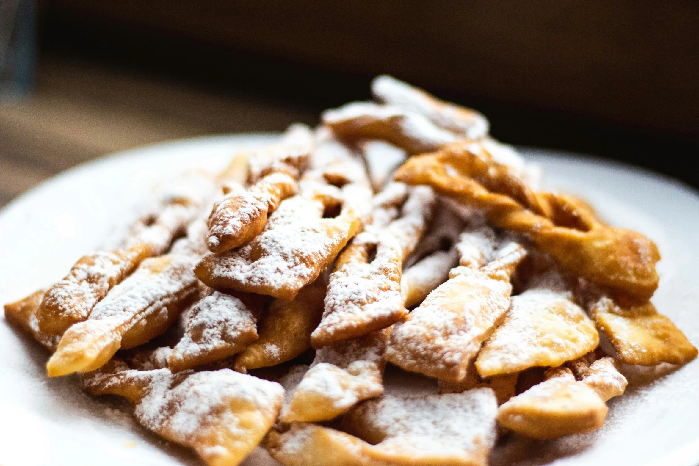 a white plate topped with waffles covered in powdered sugar, by Daniel Lieske, unsplash, renaissance, scorpion tail, traditional corsican, piled around, zig zag