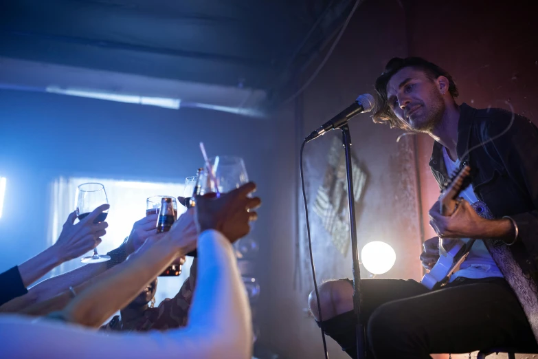 a man that is sitting in front of a microphone, by Jay Hambidge, pexels contest winner, private press, glam rockers drinking wine, gig, lit from below, slide show