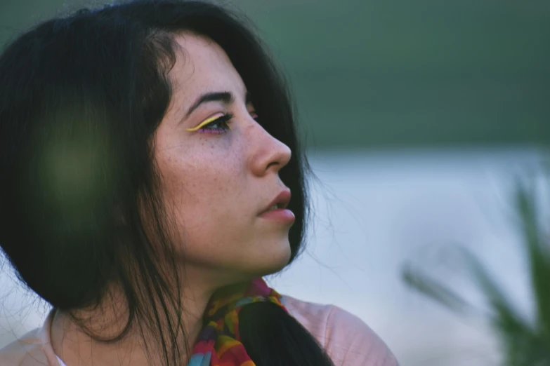 a woman standing in front of a body of water, inspired by Elsa Bleda, trending on pexels, hyperrealism, close - up profile face, young middle eastern woman, multi colored, looking up