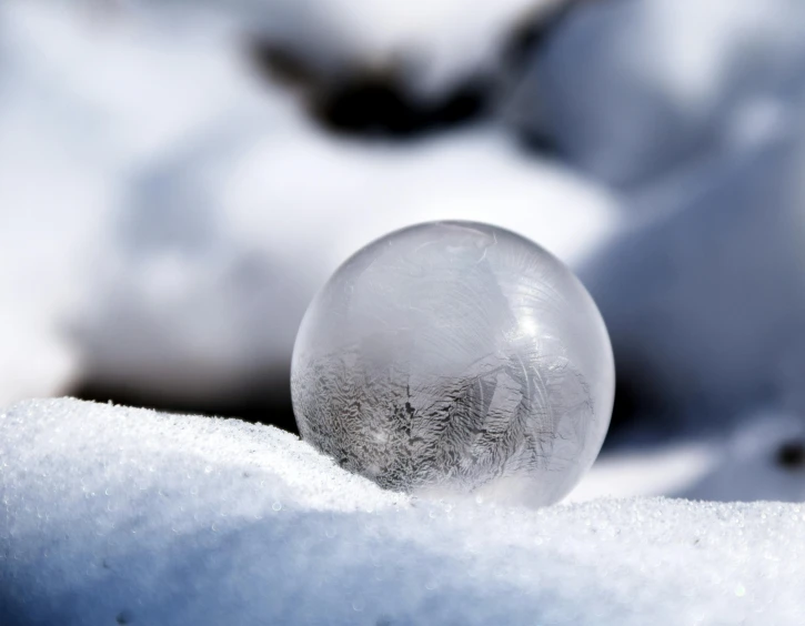 a glass ball sitting on top of snow covered ground