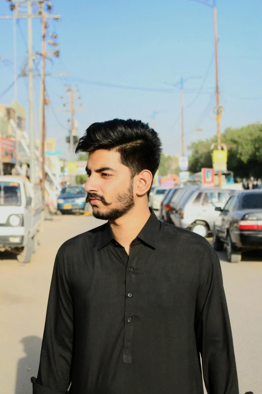 a man standing in the middle of a busy street, by Riza Abbasi, wearing a black shirt, profile photo, 2 2 years old, ((portrait))