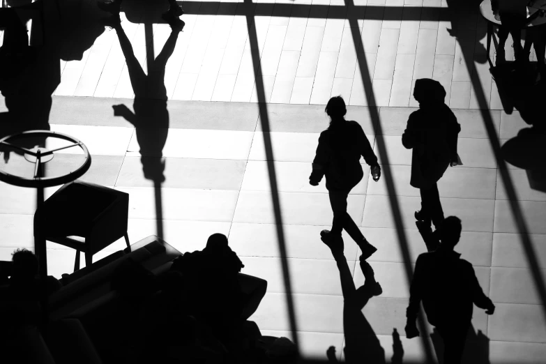 a black and white photo of people walking through a lobby, by Tobias Stimmer, outlined silhouettes, getty images, winter sun, people and creatures walking