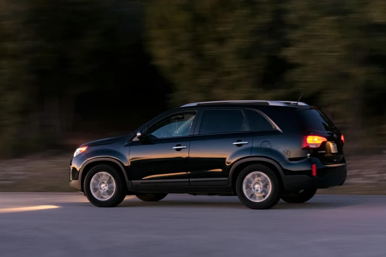 a black suv driving down a road next to a forest, renaissance, soft light from the side, square, car commercial photograph, thumbnail