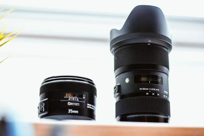 a couple of cameras sitting on top of a table, sigma lens, high quality product image”, low angle photo, lens glare