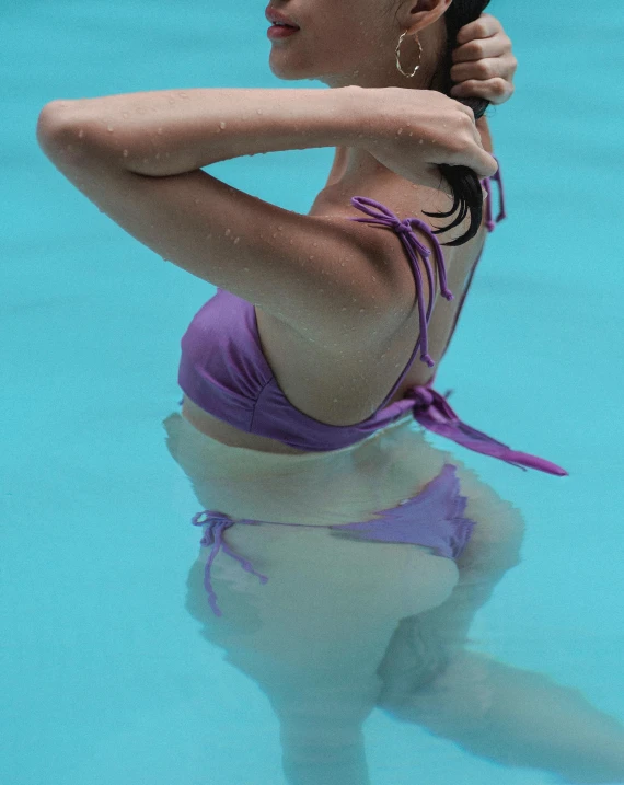 a woman in a purple bikini is standing and swimming