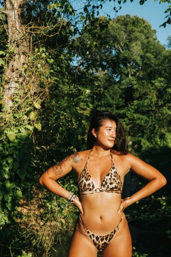 a woman in a leopard print bikini posing for a picture, by Jessie Alexandra Dick, unsplash, in front of a forest background, mai anh tran, halter top, sun overhead