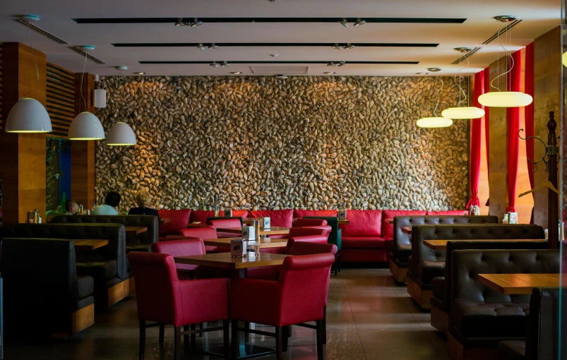 a restaurant with red chairs and a stone wall, a portrait, by Julia Pishtar, pexels, process art, sitting in a lounge, tehran, panorama, fan favorite