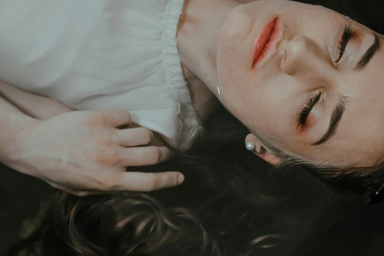 a  with red lipstick laying down with her eyes open
