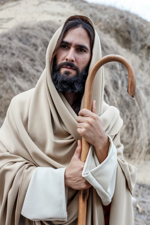 a man with a long beard holding a stick, a picture, by Everett Warner, shutterstock, dressed like jesus christ, ox, wearing white cloths, matthew benedict