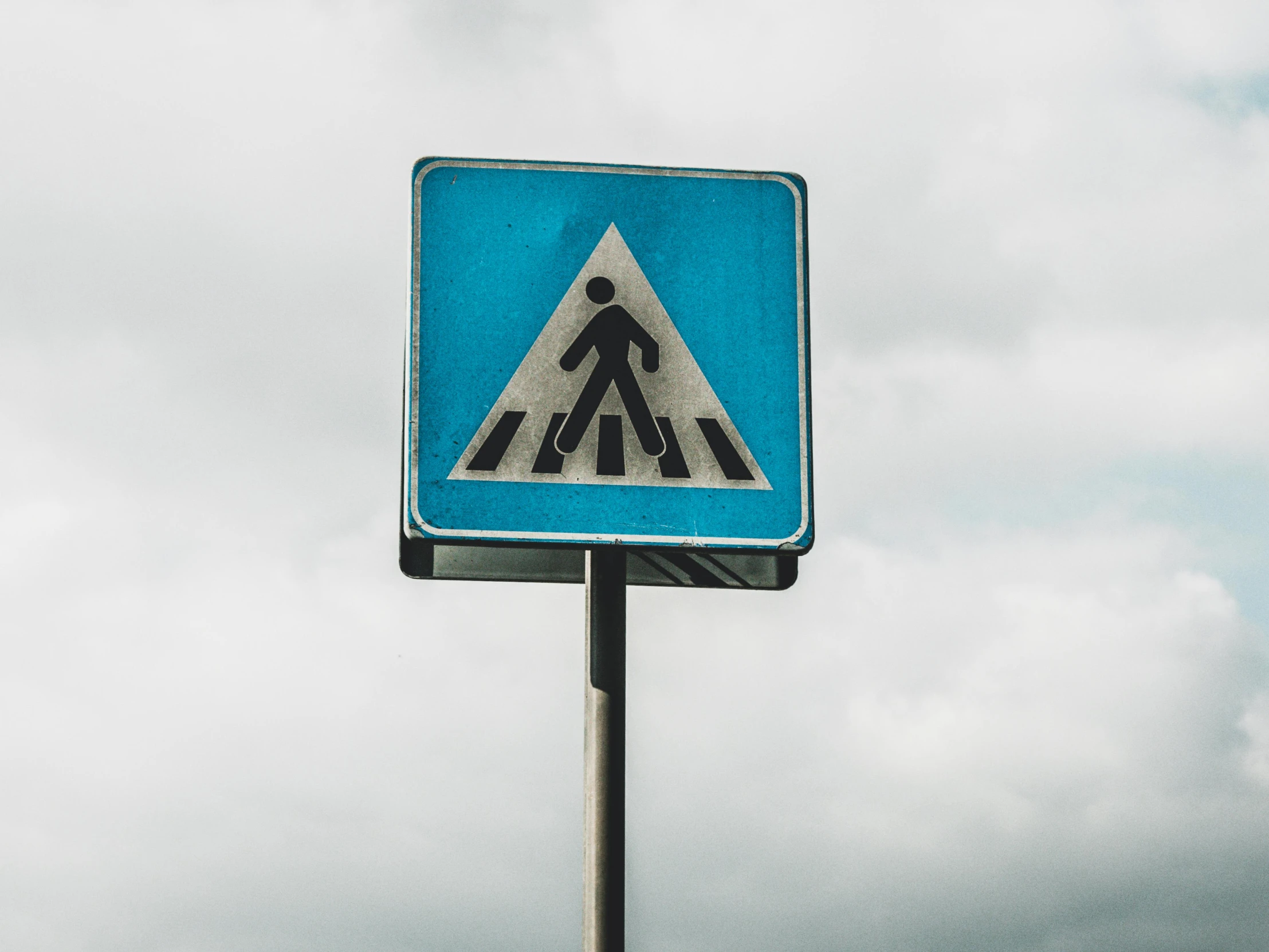 a blue and white road sign with the sky and clouds in the background