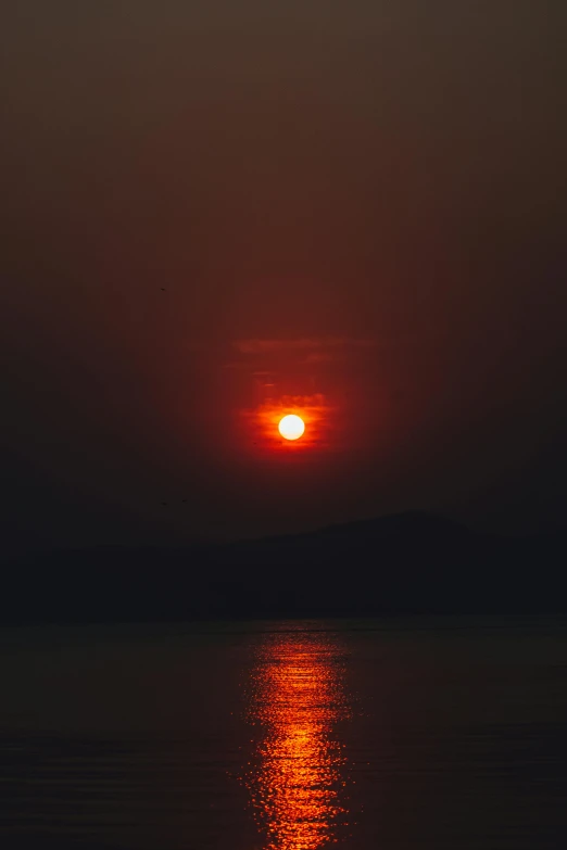 the sun setting over a body of water, by Aguri Uchida, pexels, very smoky, red sun over paradise, india, greece