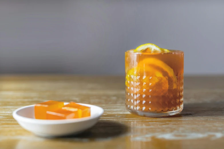 a bowl of orange zest is sitting next to a glass filled with a drink