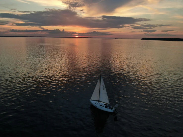 small white boat floating on open water during sunset