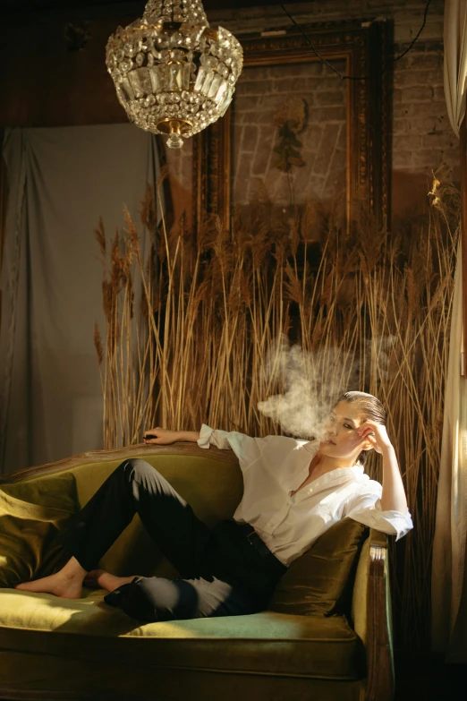 man laying on a green sofa smoking a cigarette