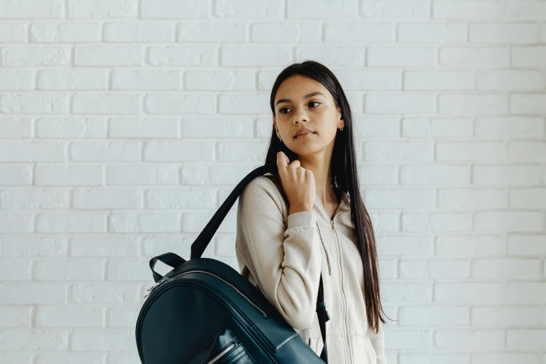 a woman with a backpack standing in front of a brick wall, trending on pexels, happening, background image, girl in studio, school bag, avatar image