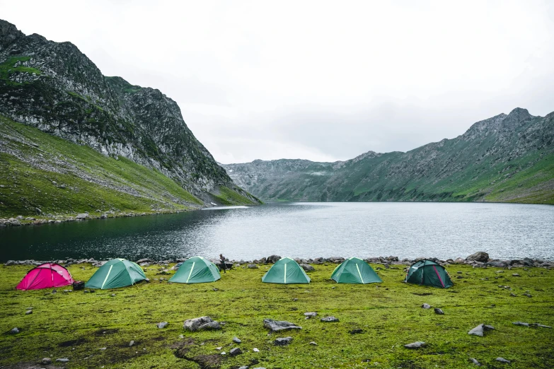 a group of tents sitting on top of a lush green field, pexels contest winner, hurufiyya, fjord, grey, small lake, conde nast traveler photo