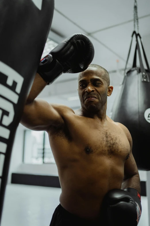 a man standing next to a punching bag, a photo, by Clifford Ellis, instagram post, chest guard, trevor phillips, center focused