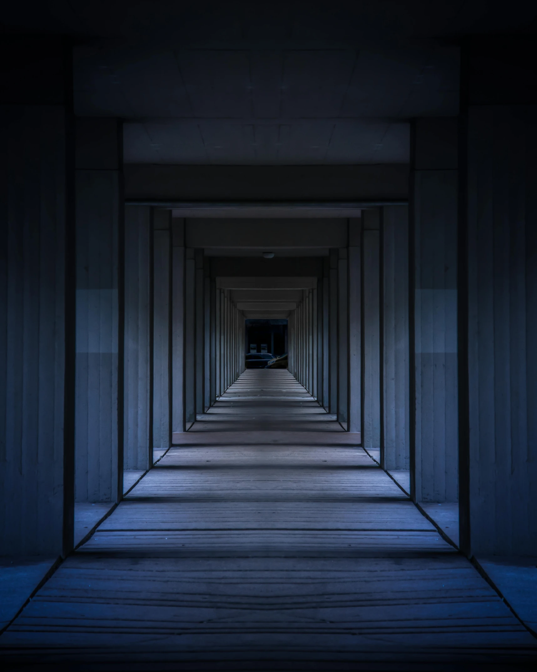 an empty walkway with a lot of pillars between two sets