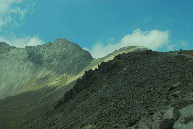 a mountain with rocks and grass below it