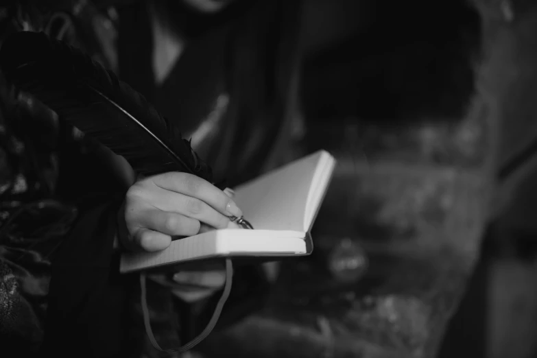 a person holding a pen while writing in an open book