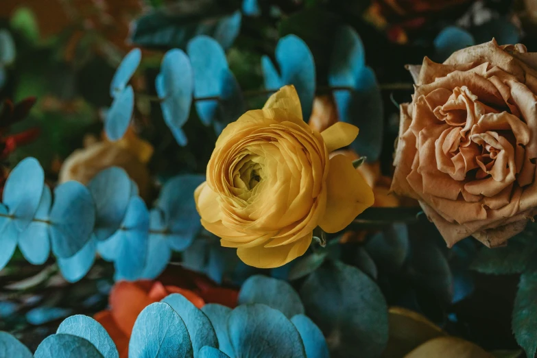 two small flowers in a vase by some blue and orange plants