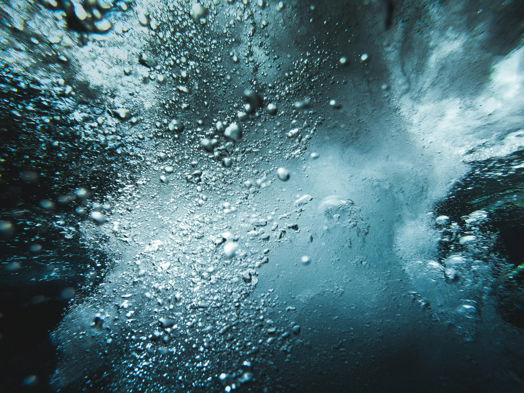 a large body of water with bubbles coming out of it, an album cover, inspired by Elsa Bleda, unsplash, abstract expressionism, in an icy cavern, high angle close up shot, hyperrealistic octane render, burst of powders