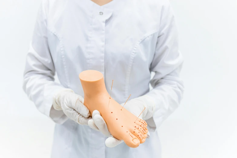 a close up of a person holding a plastic object, acupuncture treatment, art toys on feet, wearing lab coat and a blouse, terracotta