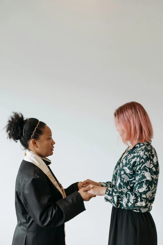 two women standing next to each other in a room, trending on unsplash, visual art, ceremony, with pink hair, ring, set against a white background