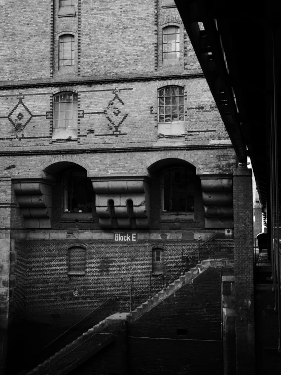 a black and white photo of a building, a black and white photo, inspired by Henri Cartier-Bresson, graffiti, they are watching, robert maplethorpe, under bridge, brick
