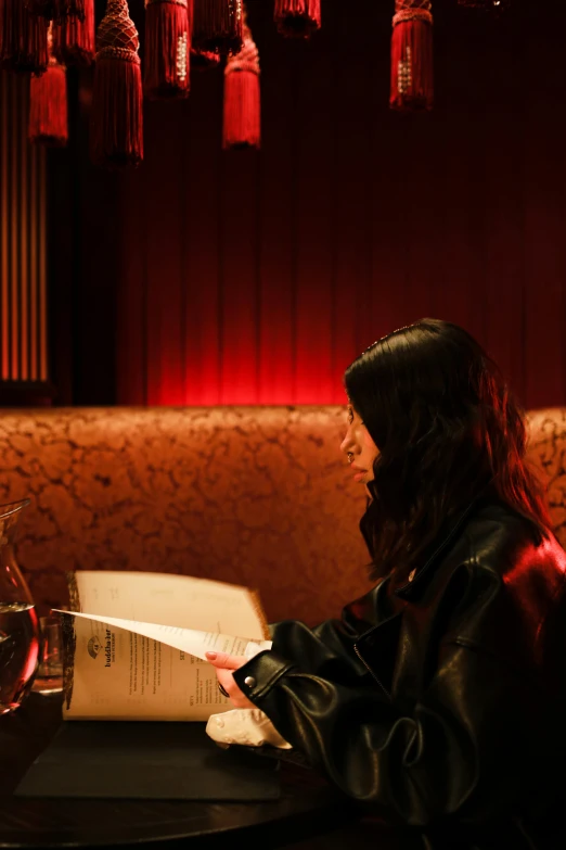 a woman sitting at a table with a glass of wine, red lighting, reading, closed limbo room, gemma chen