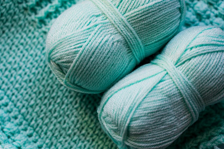 a pair of yarn balls are displayed on an afghan