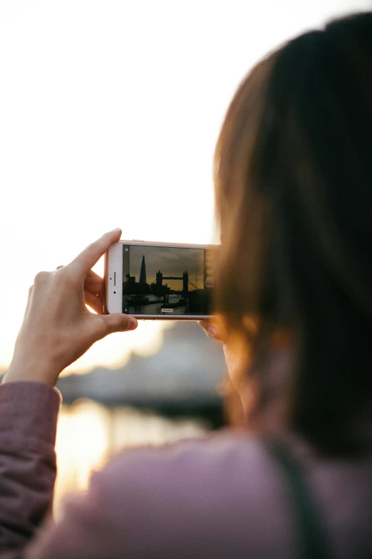 a woman taking a picture with her cell phone, a picture, pexels contest winner, temples behind her, sundown, with a sleek spoiler, zoomed in shots