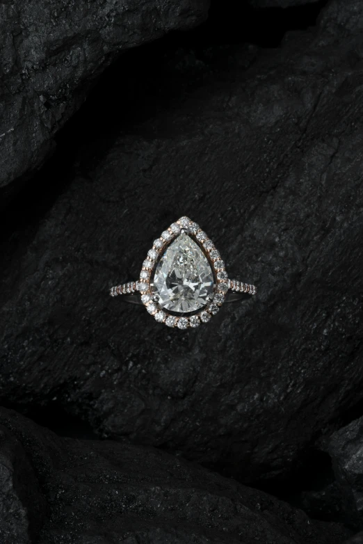 a pear shaped diamond ring sitting on top of a pile of rocks, pexels contest winner, renaissance, on black background, [ cinematic, mint, thumbnail