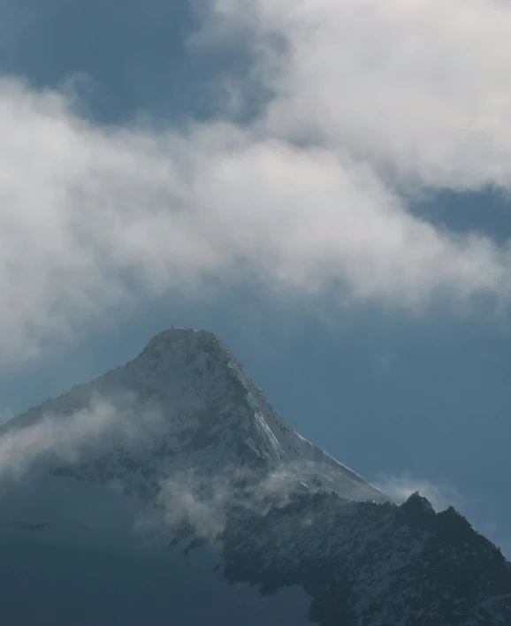 the top of a snowy mountain with a bird flying above