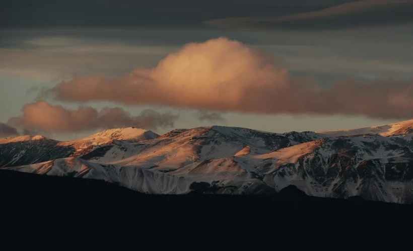 the snow capped mountains glow behind them as the sun sets