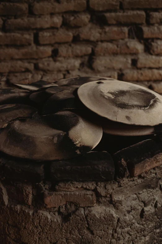 a pile of mushrooms sitting on top of a wooden table, a still life, inspired by Károly Markó the Elder, trending on unsplash, arte povera, an oversized beret, pan and plates, partially covered with dust, burned