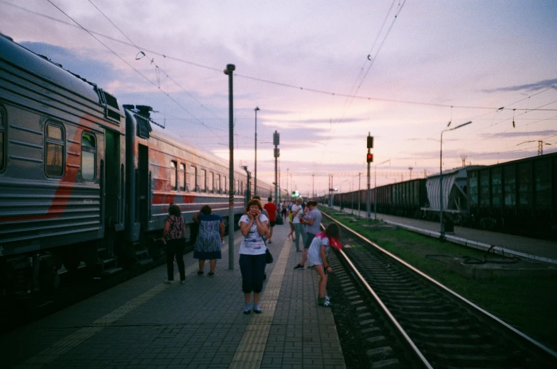 a group of people walking next to a train, by Anna Haifisch, pexels contest winner, realism, summer evening, typical russian atmosphere, square, 🚿🗝📝