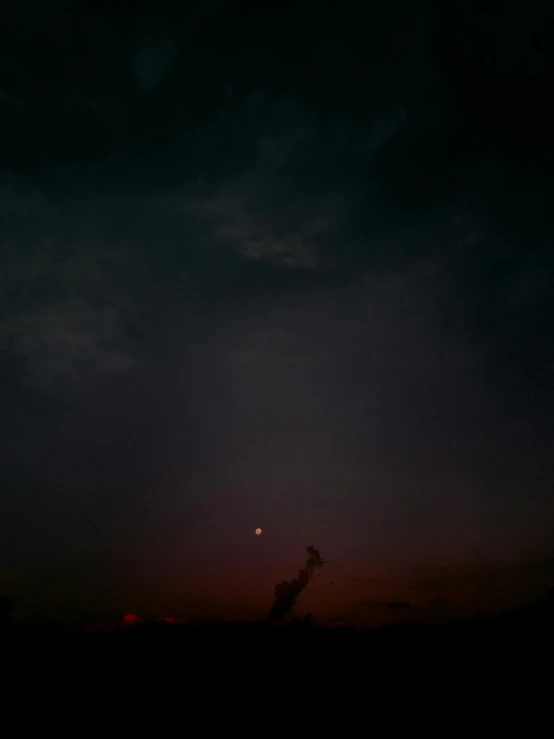 the sun setting in the dark sky with clouds