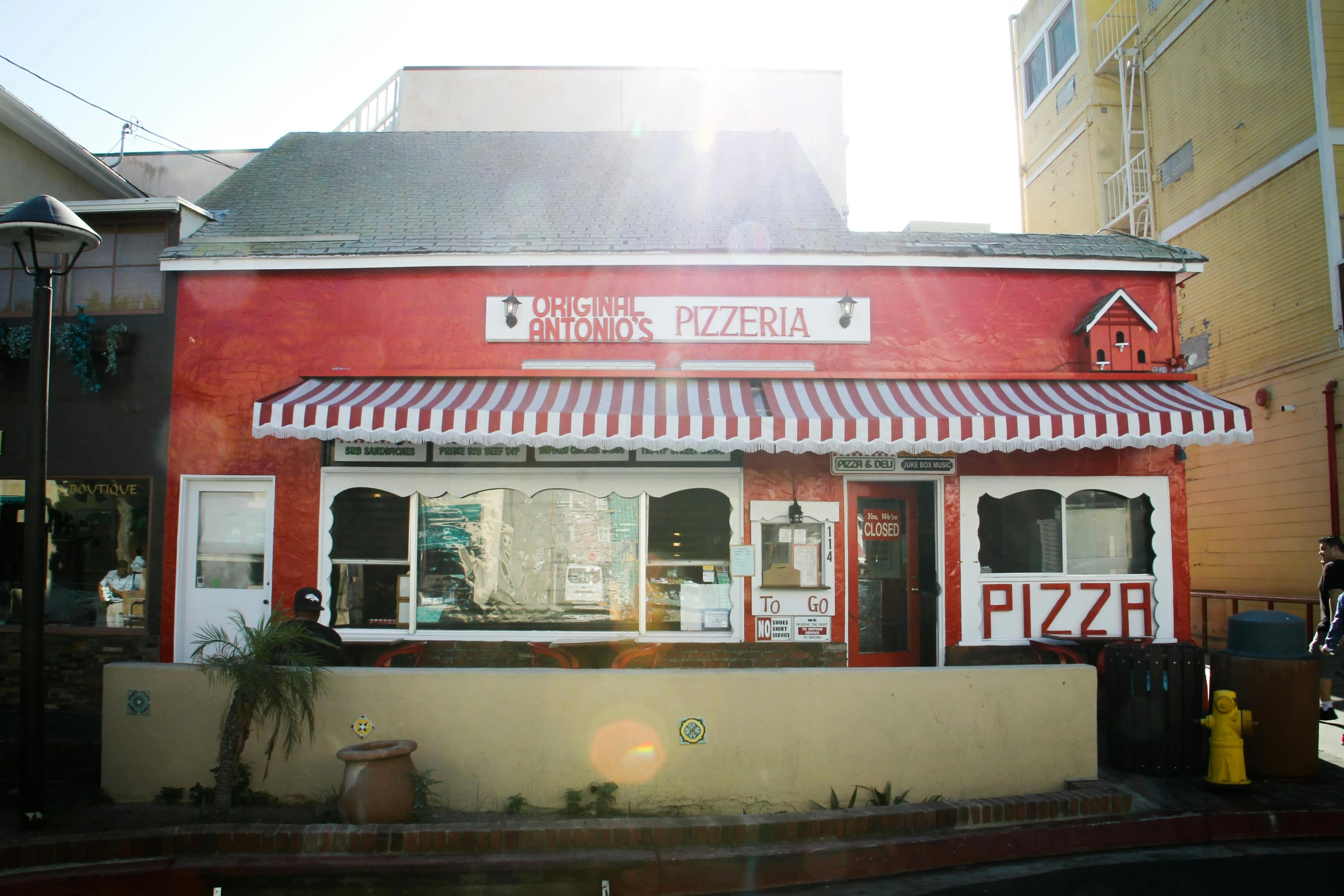 a red and white restaurant sitting on the side of a road, pizza on a table, miguel angel, verbena, oceanside