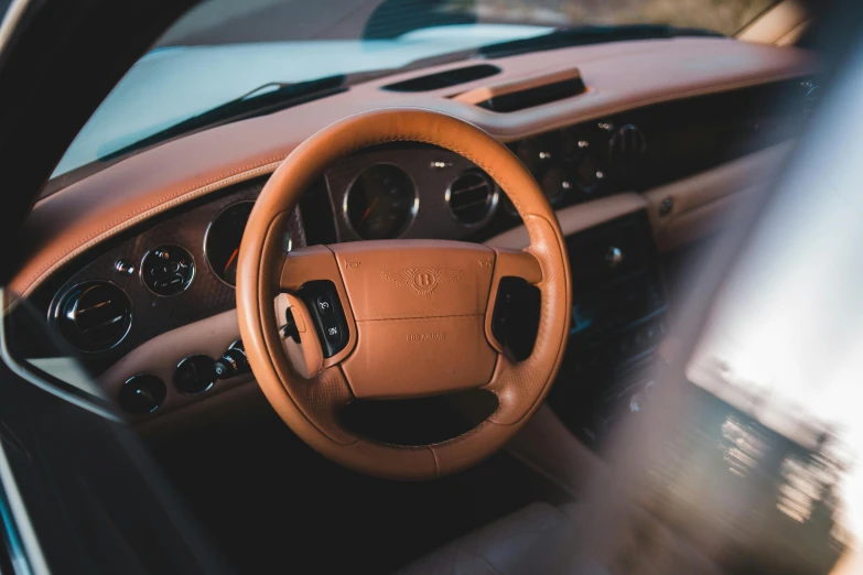 a close up of a steering wheel in a car, an album cover, inspired by Harry Haenigsen, trending on unsplash, renaissance, wearing a brown leather coat, taken in 1 9 9 7, jony ive, sports car in the room