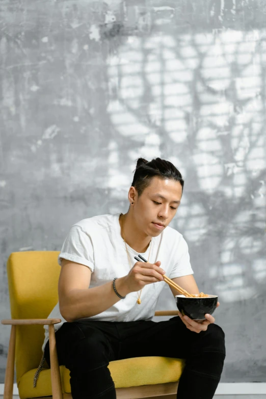 a man sitting in a chair eating a bowl of noodles, inspired by Fei Danxu, pexels contest winner, minimalism, handsome man, an asian woman, profile pic, promo image