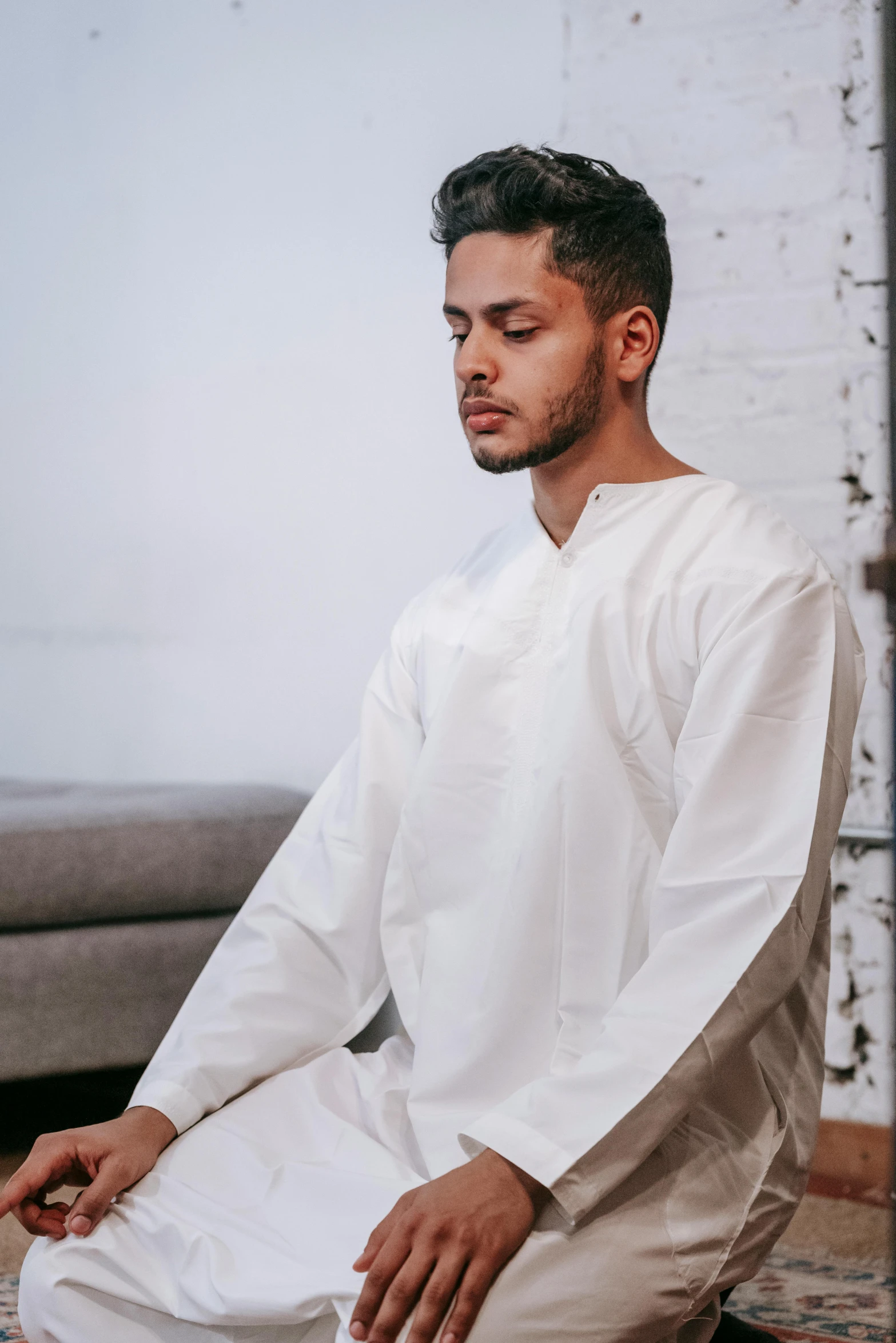 a man in white sits with his hands crossed