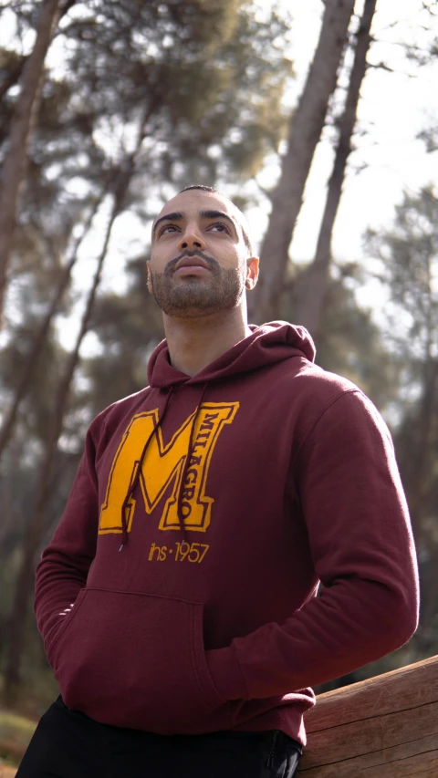 a man wearing a maroon sweatshirt with a yellow m on it