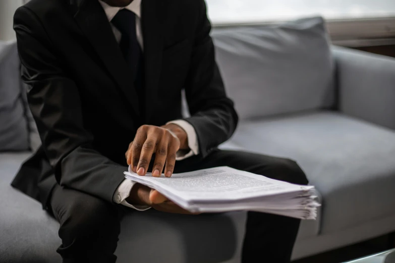 a man in a suit sitting on a couch, pexels contest winner, private press, confidential documents, man is with black skin, selling insurance, background image