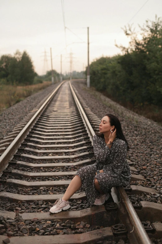 a woman sitting on a train track talking on a cell phone, by Lucia Peka, trending on pexels, realism, ukrainian, instagram story, 15081959 21121991 01012000 4k