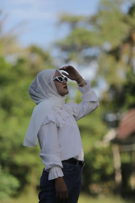 a woman standing on top of a lush green field, by Basuki Abdullah, hurufiyya, in sun glasses, in white clothes, during an eclipse, street photo