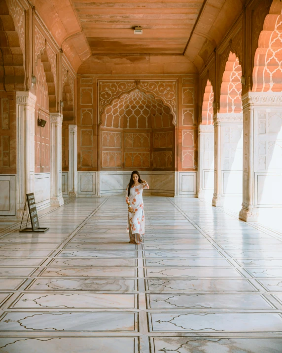 a woman in a long dress standing in a building, unsplash contest winner, arabesque, red and white marble panels, india, delightful surroundings, architectural digest photo