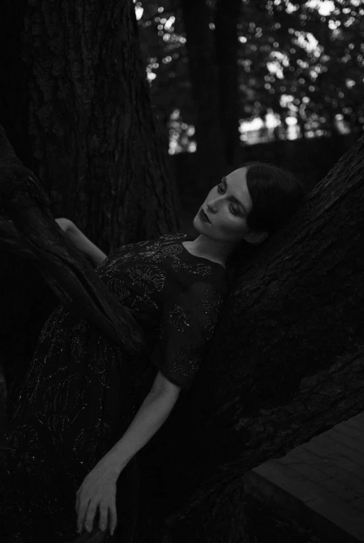 a black and white photo of a woman leaning against a tree, inspired by irakli nadar, tumblr, ((portrait)), anna nikonova, midnight, resting