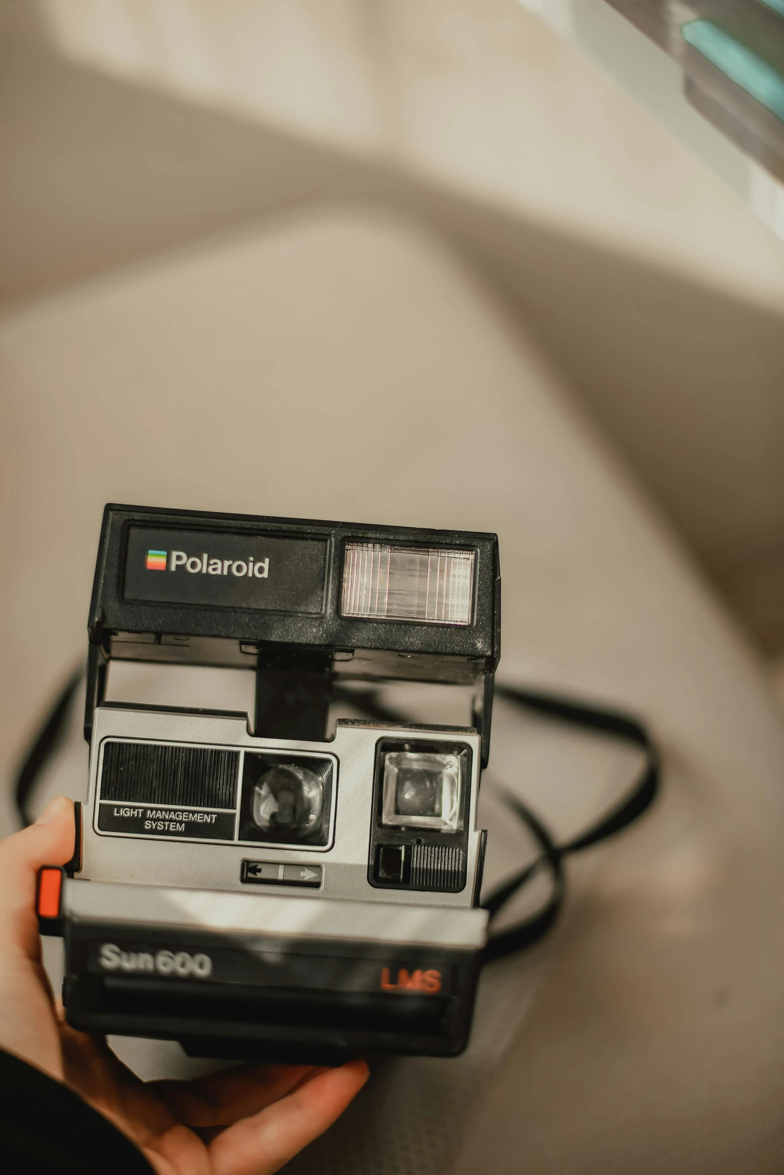 a person holding a polaroid camera in their hand, inspired by Elsa Bleda, unsplash, holography, low quality photo, vhs camcorder footage, polaroid 6 0 0, a high angle shot