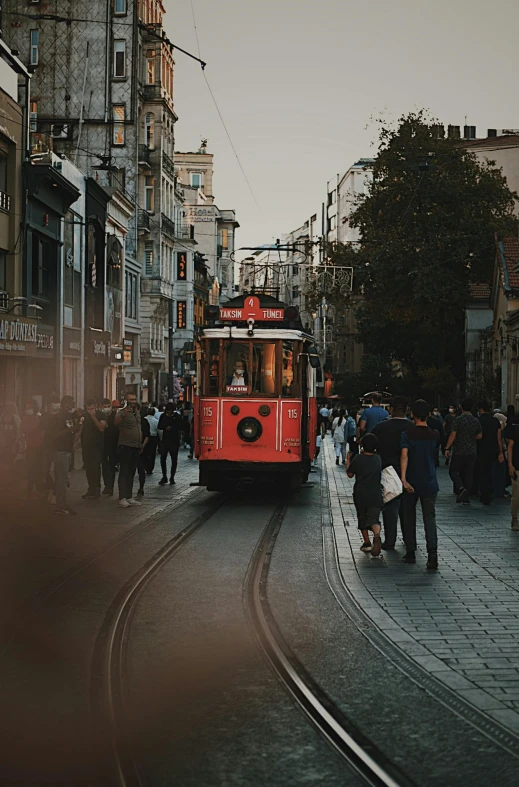 a red trolley traveling down a street next to tall buildings, by irakli nadar, pexels contest winner, happening, crowds of people, turkey, square, a quaint